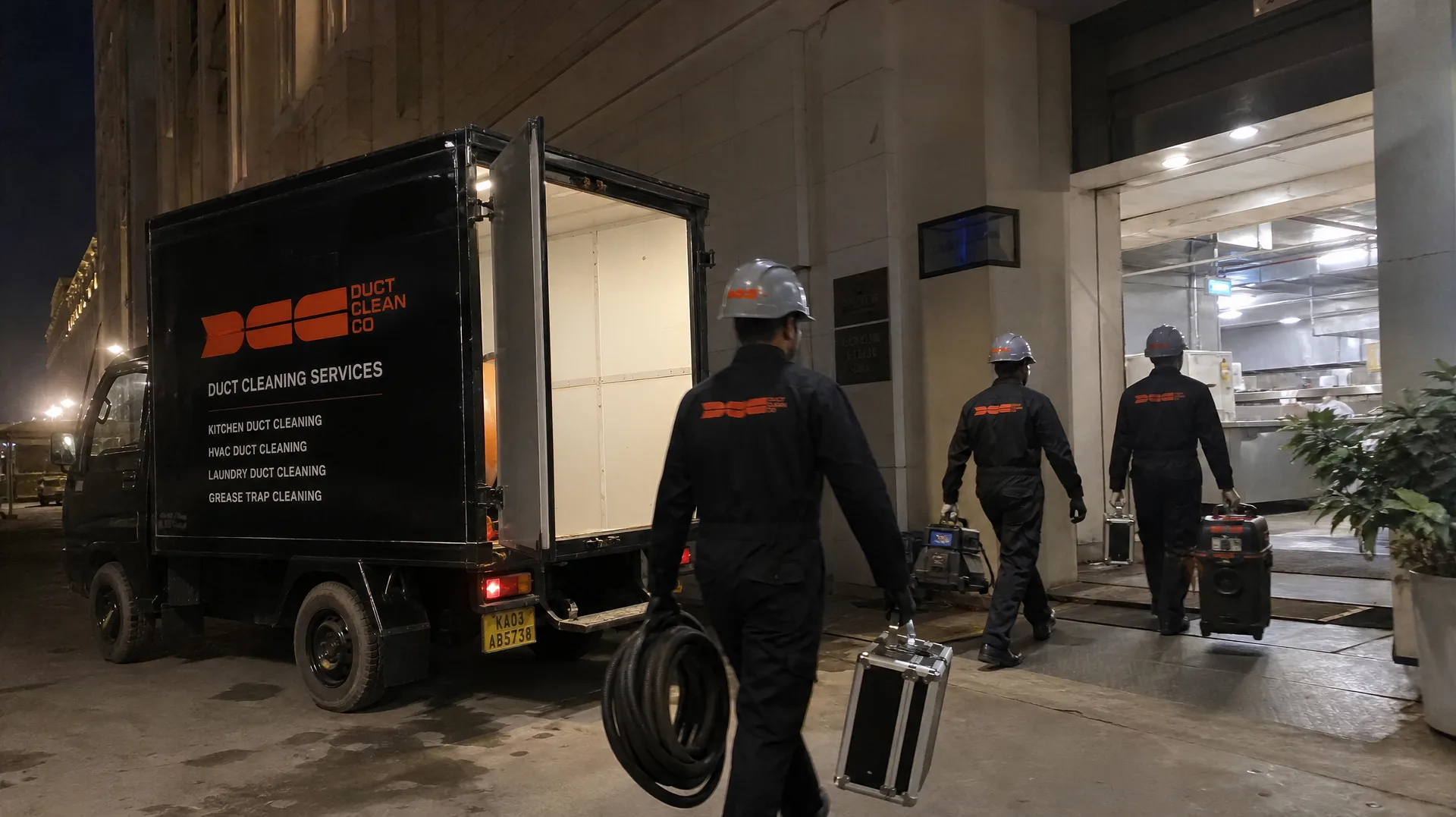 DCC crew carrying equipment cases from the branded DCC service truck into a night-shift site